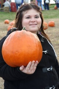A photo of a young woman holding a pumpkin 