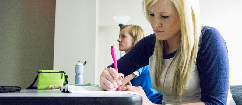 A student focusing hard and taking notes in class.