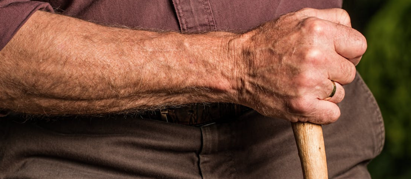 A close up image of an elderly man's arm holding a cain. Fitness trainers can share the benefits of staying active. If you're interested, call WellSpring today.