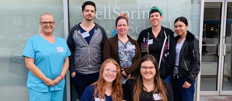 A group of students and teachers stand outside WellSpring School of Allied Health