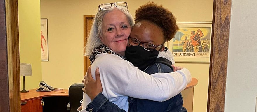 WellSpring student and staff member hugging.